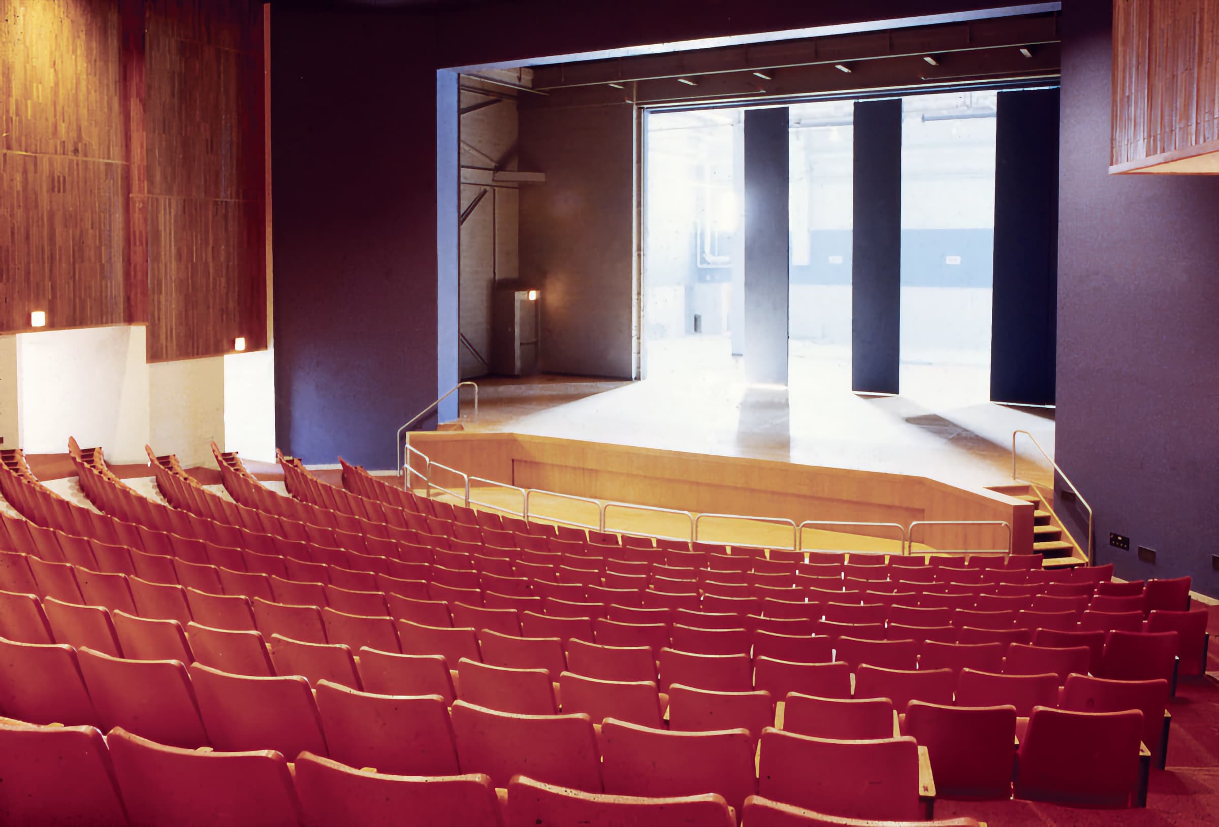 Maguire Theatre house in Old Westbury, NY — red velvet seating tiers facing the stage, the room your dancer will perform in