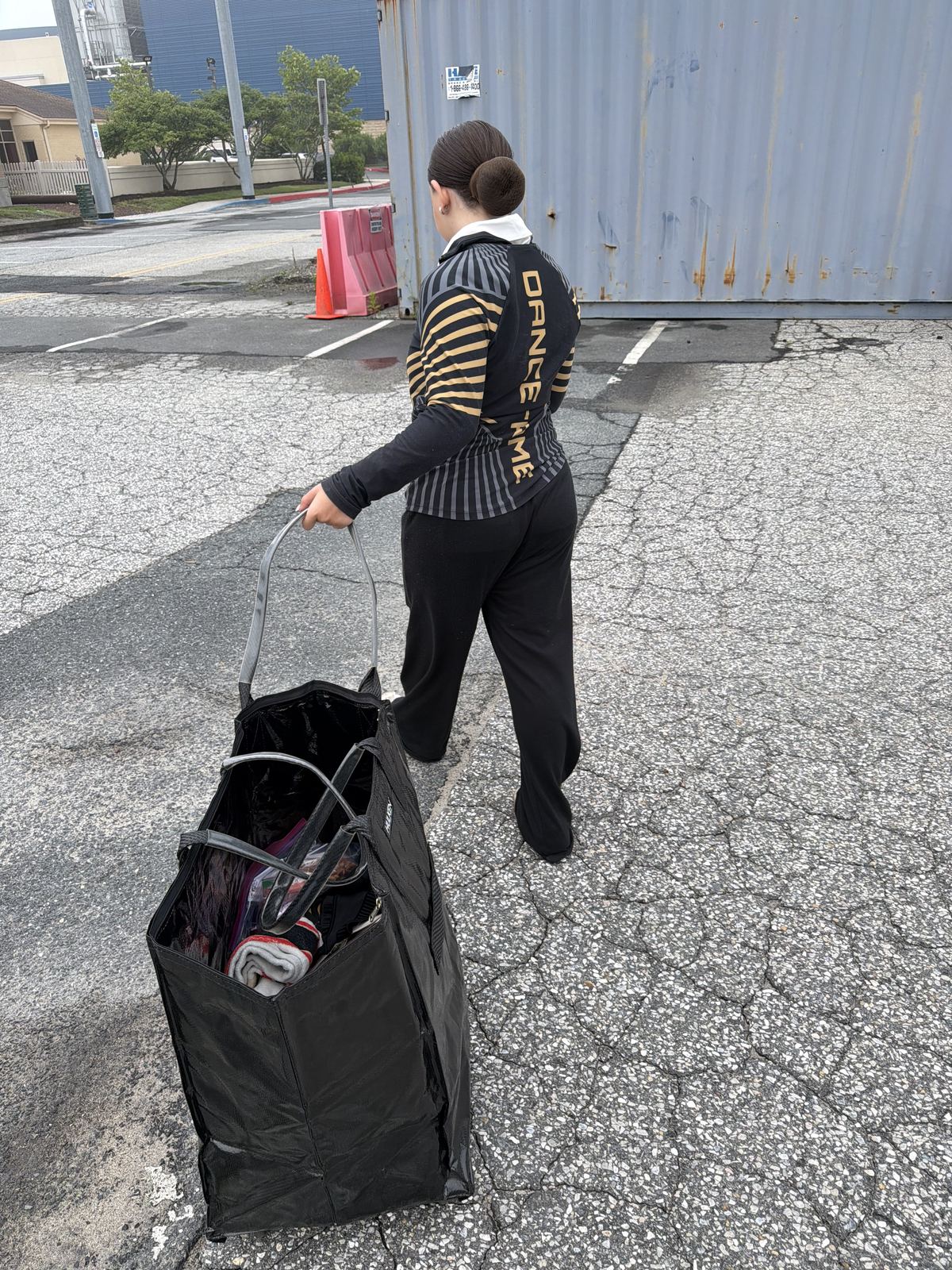 A DXNY dancer wheeling a costume rack bag into the convention center at Nationals