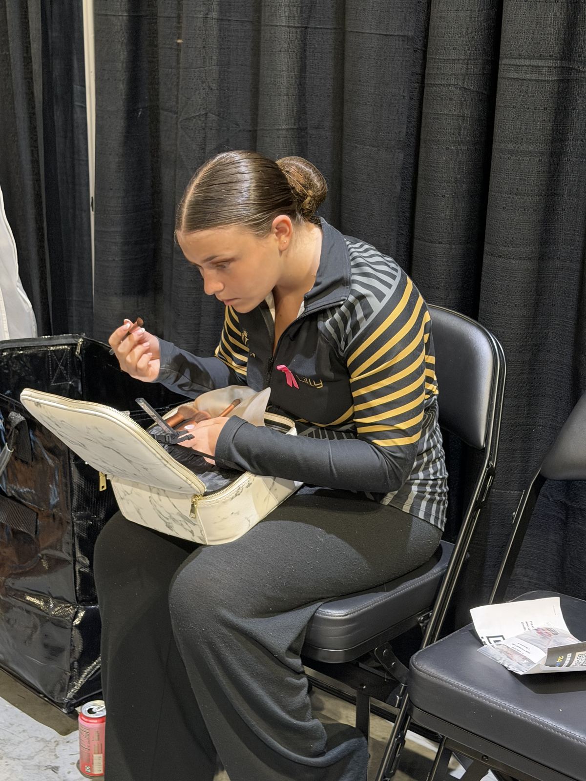 A DXNY dancer doing her own competition makeup backstage at Nationals