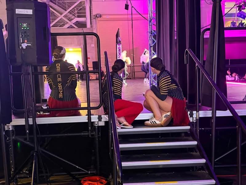DXNY dancers sitting on the side stage steps watching another routine at Nationals